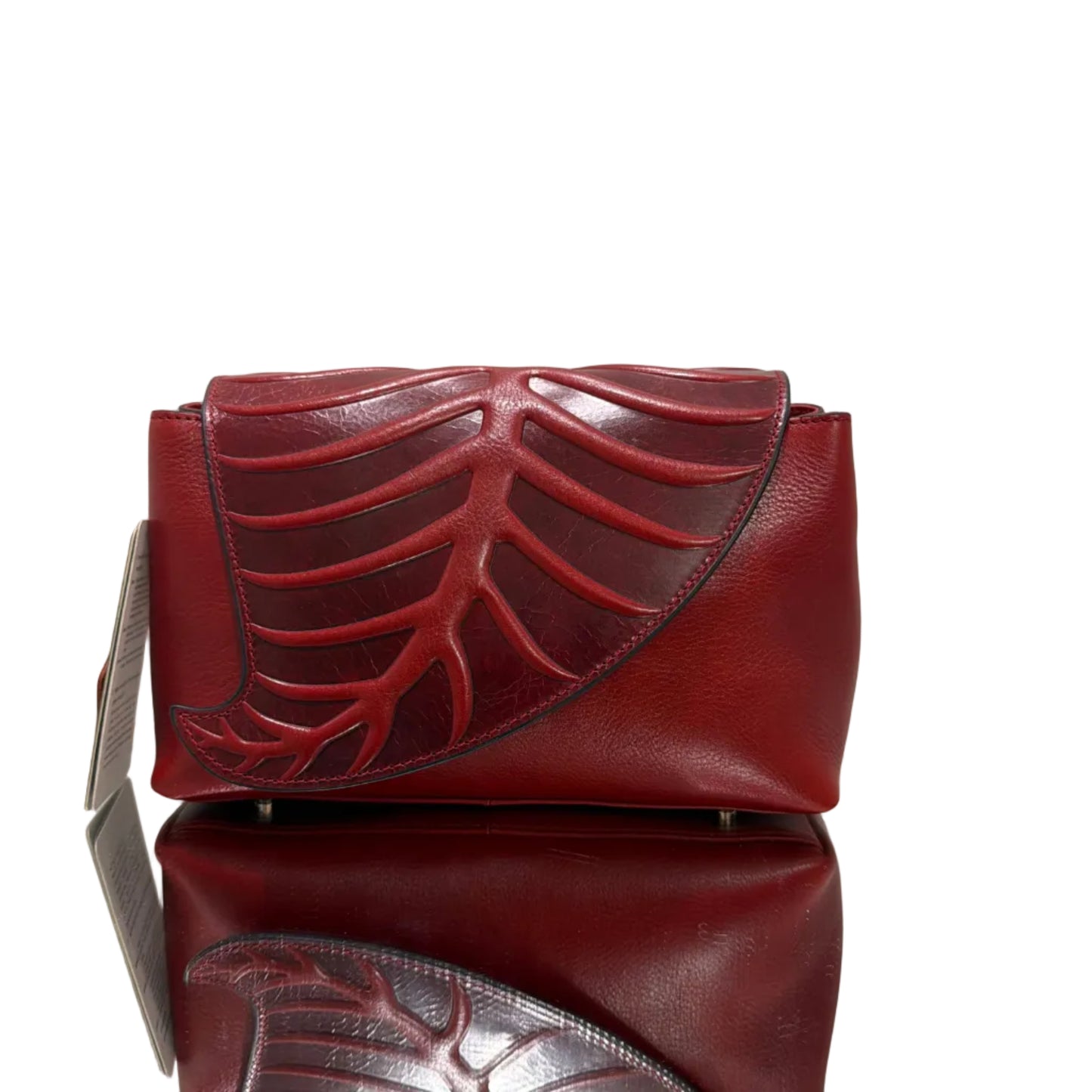 Red leather clutch bag with intricate design on a light background