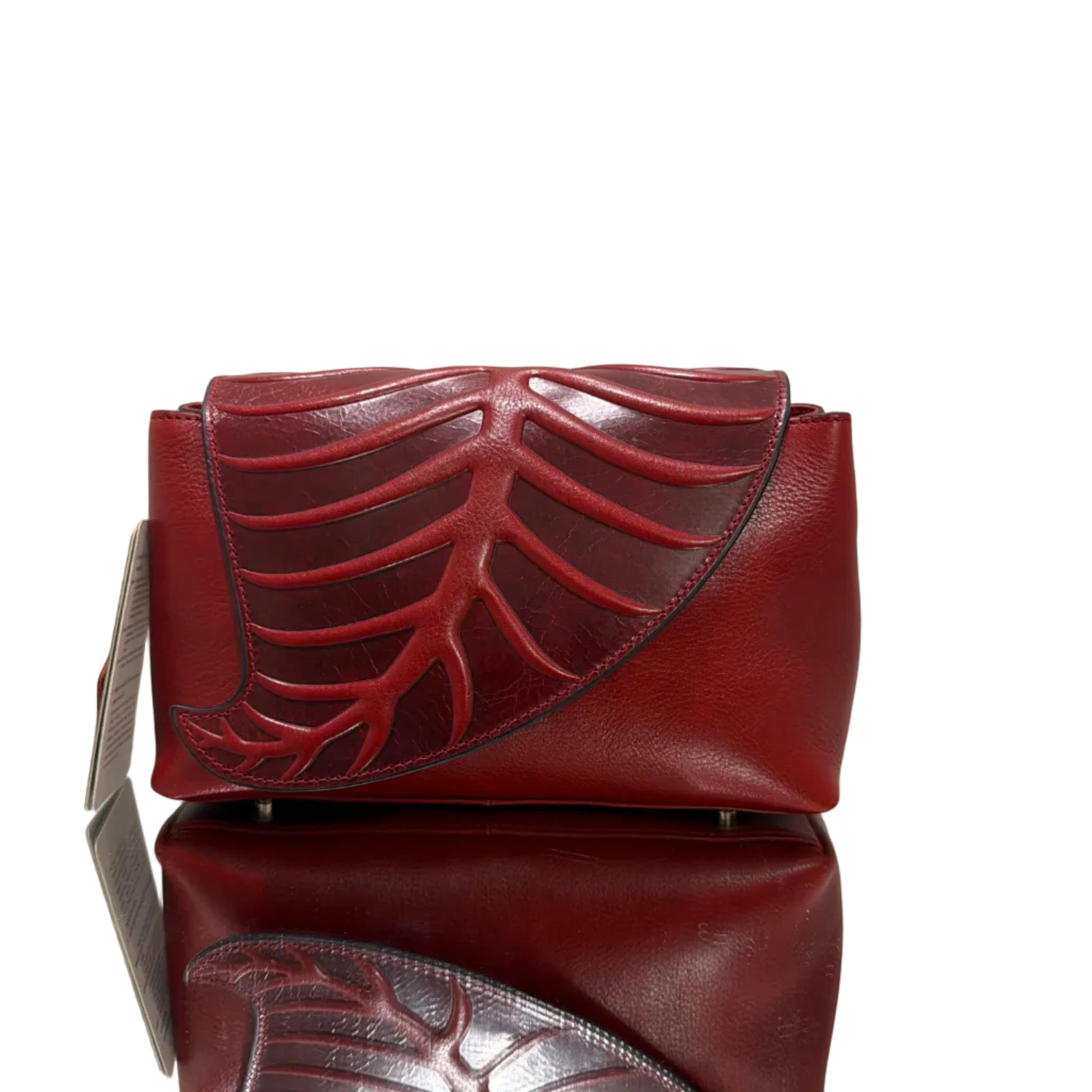 Red leather clutch bag with intricate design on a light background