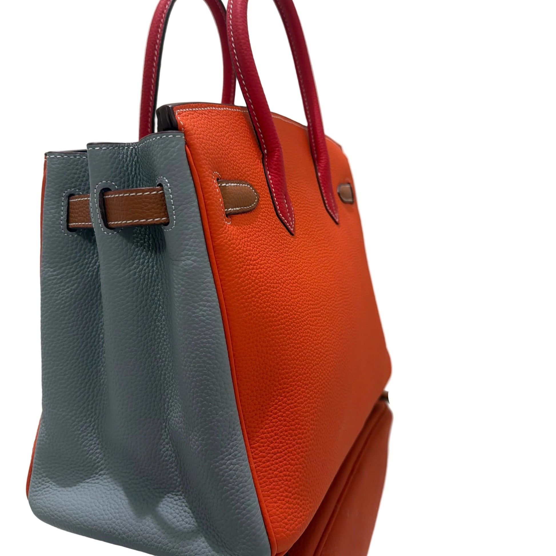Two leather handbags, one orange and one gray, on a white surface.