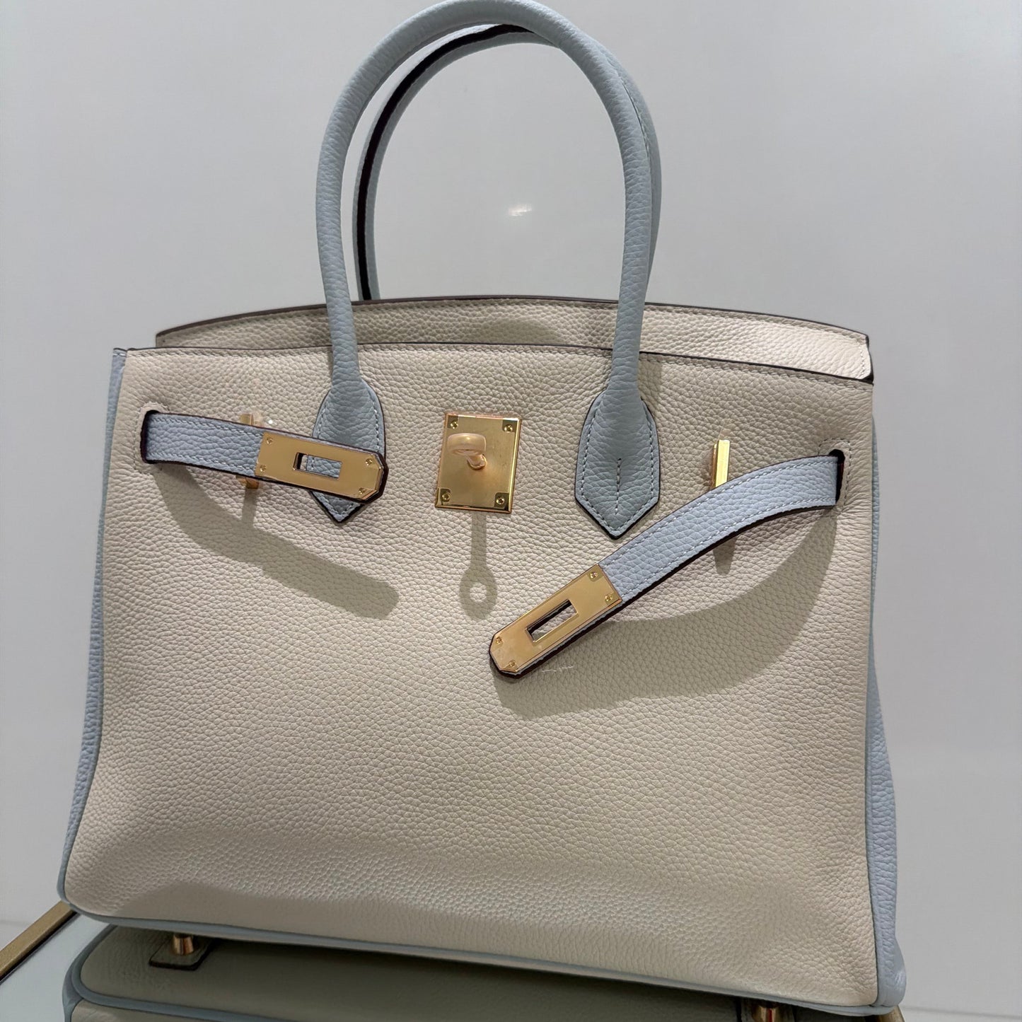Beige handbag with gold hardware on a light gray background