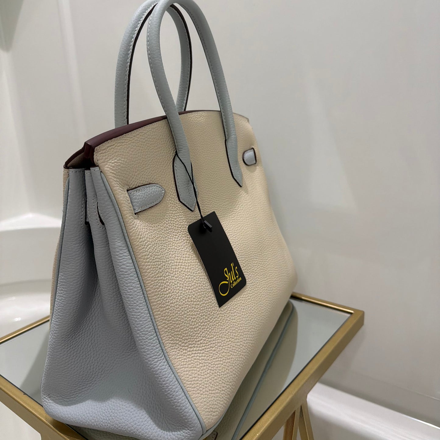 Beige handbag with a black tag on a white background