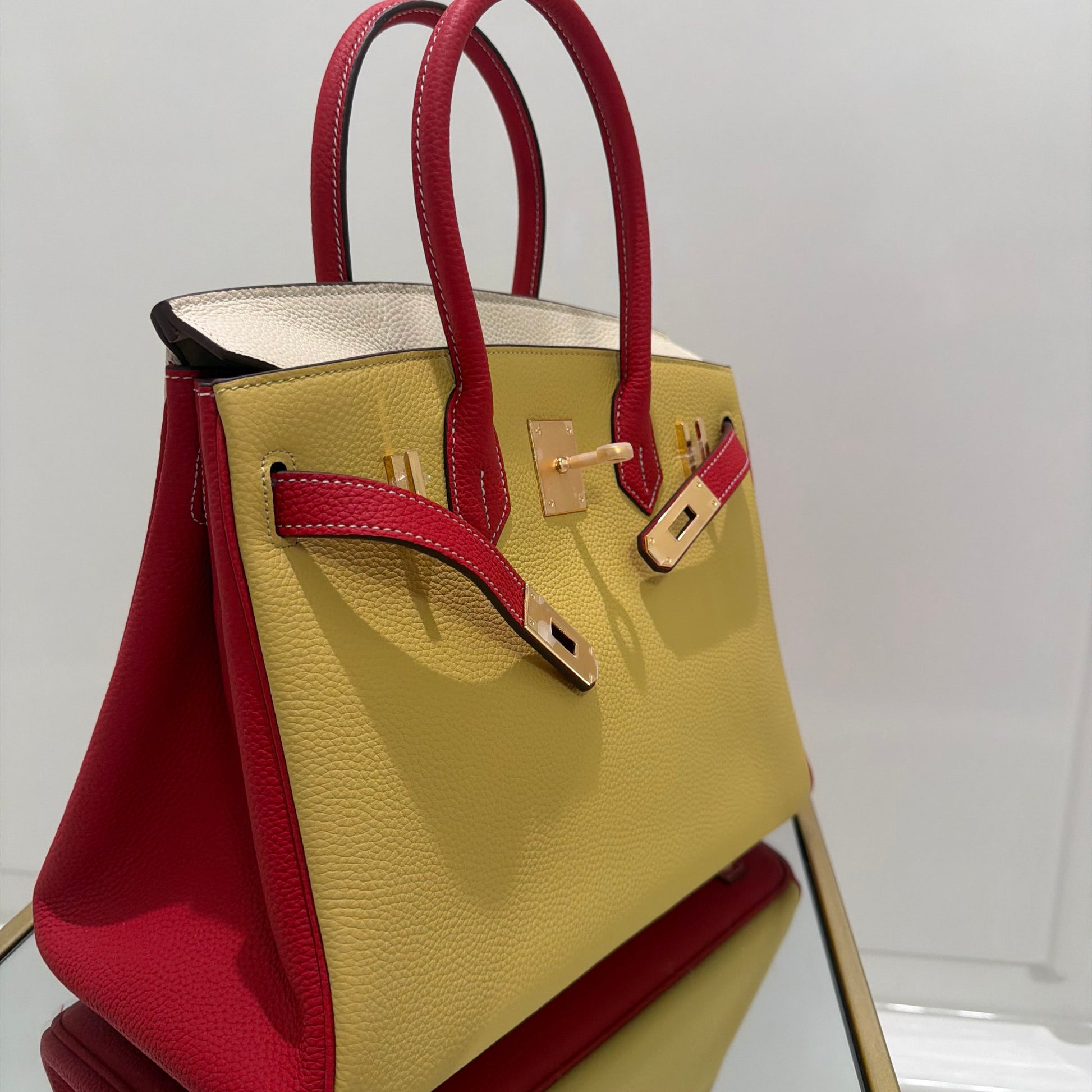 Gold and red handbag on a stand against a white background