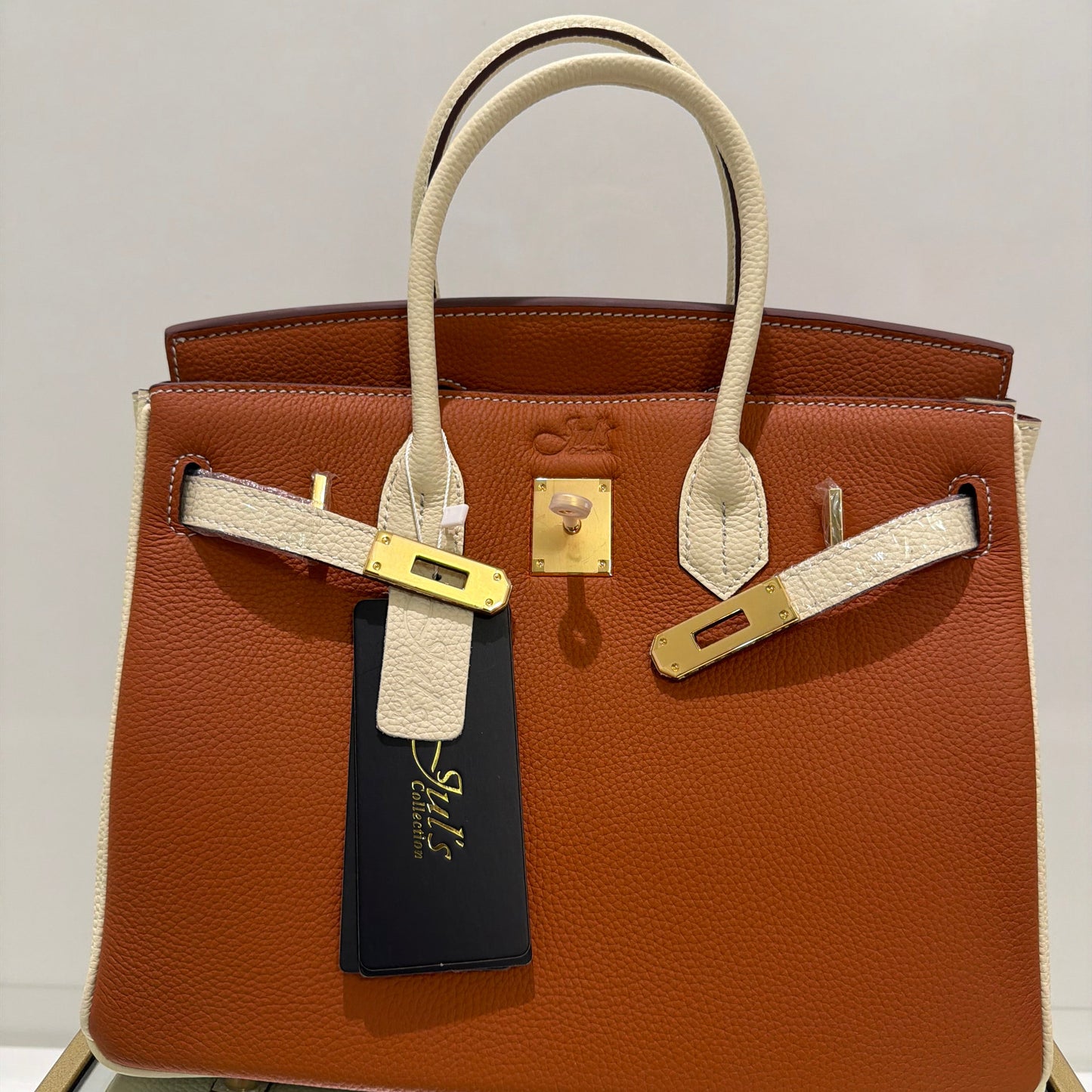 Brown leather handbag with gold hardware on a light gray background