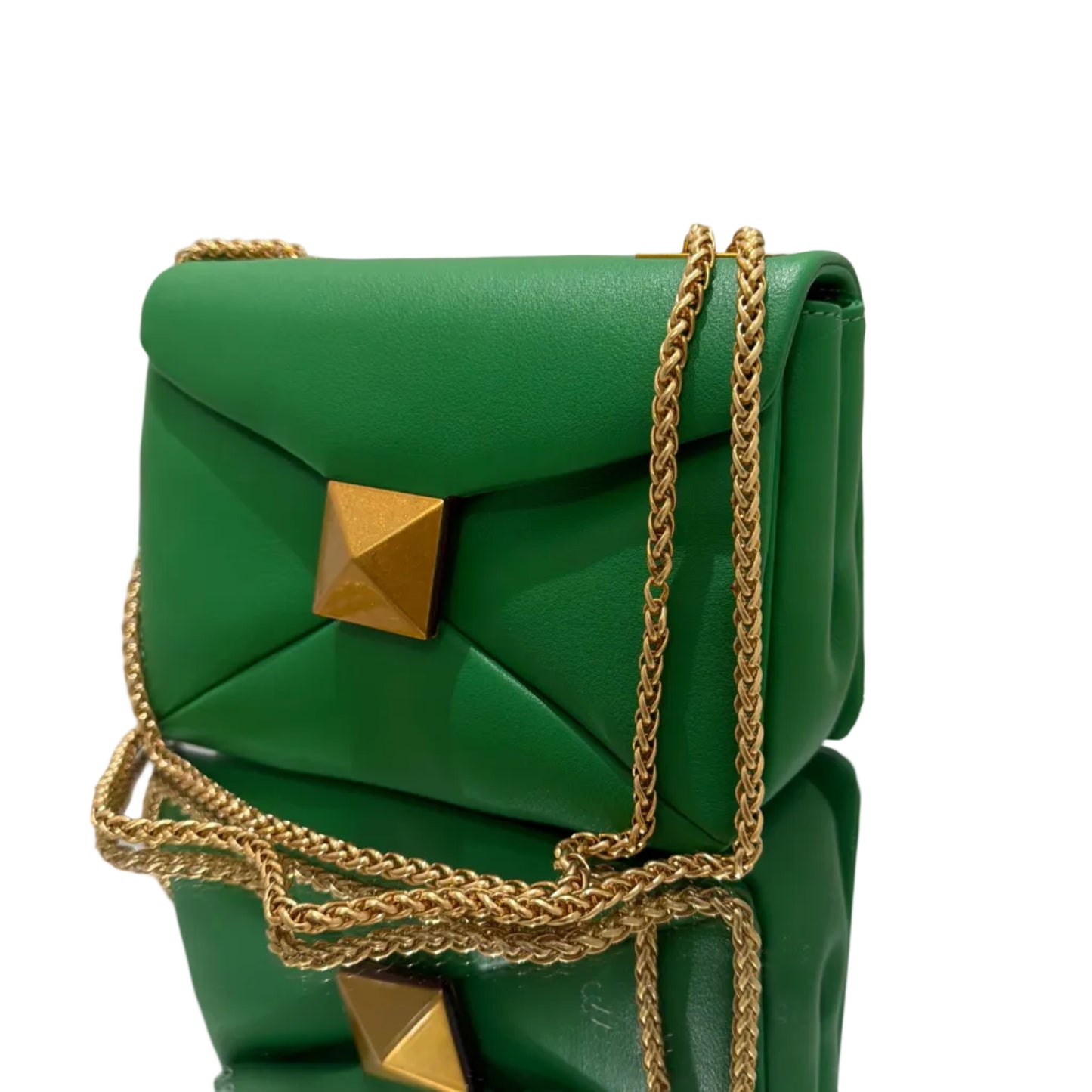 Green handbag with gold chain and studs on a white surface