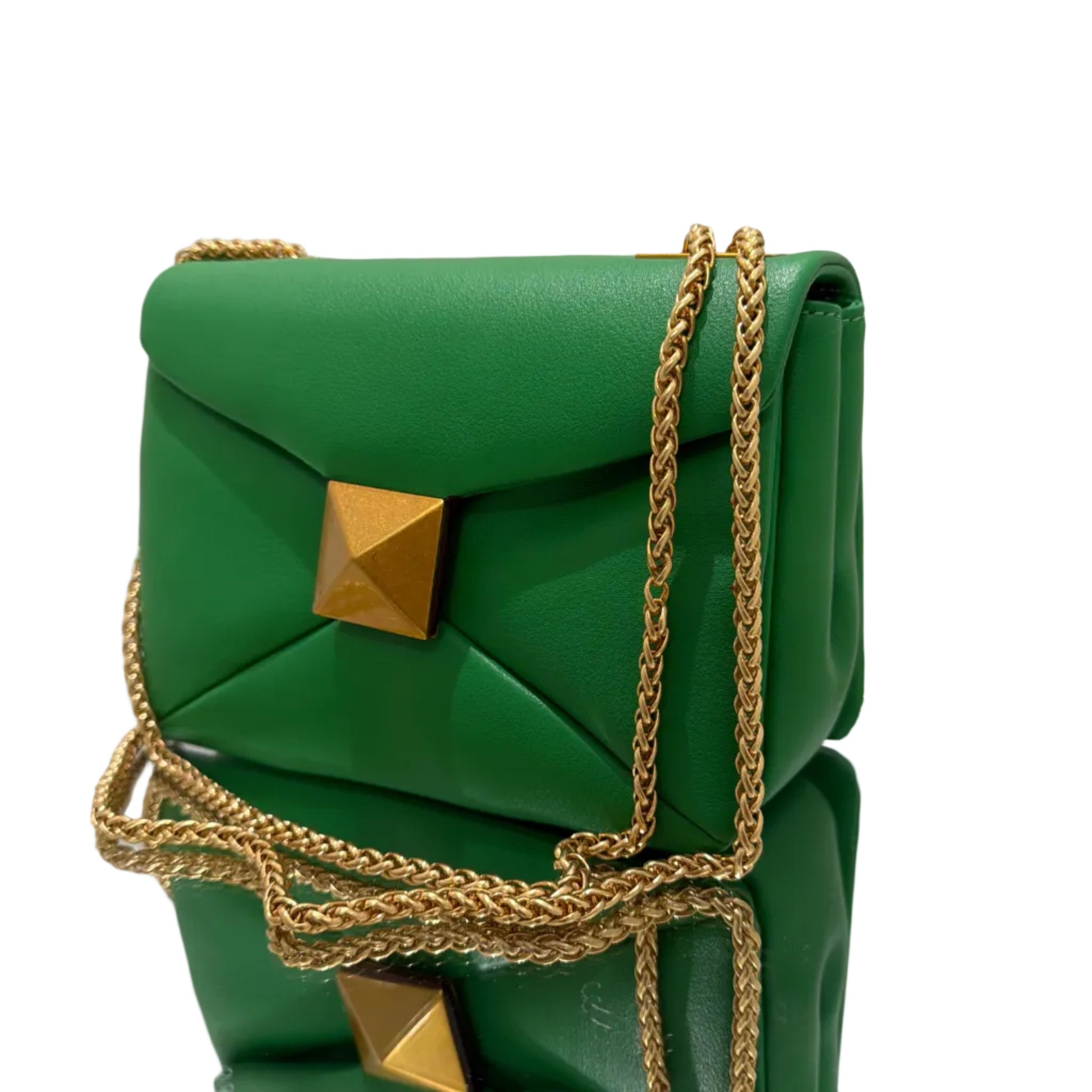 Green handbag with gold chain and studs on a white surface
