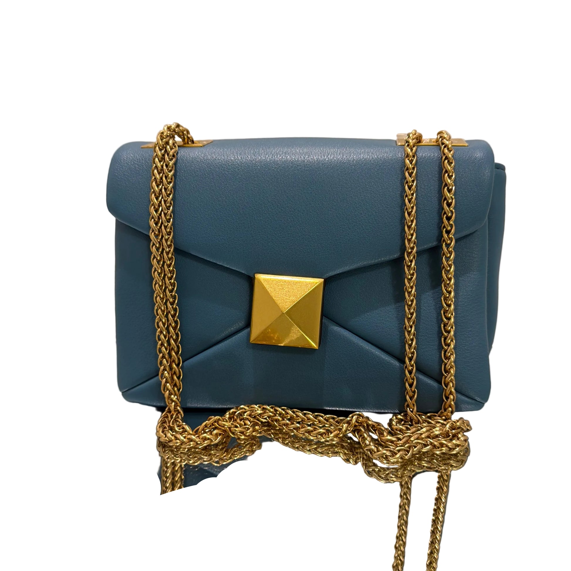 Blue clutch bag with gold chains and accents on a beige background