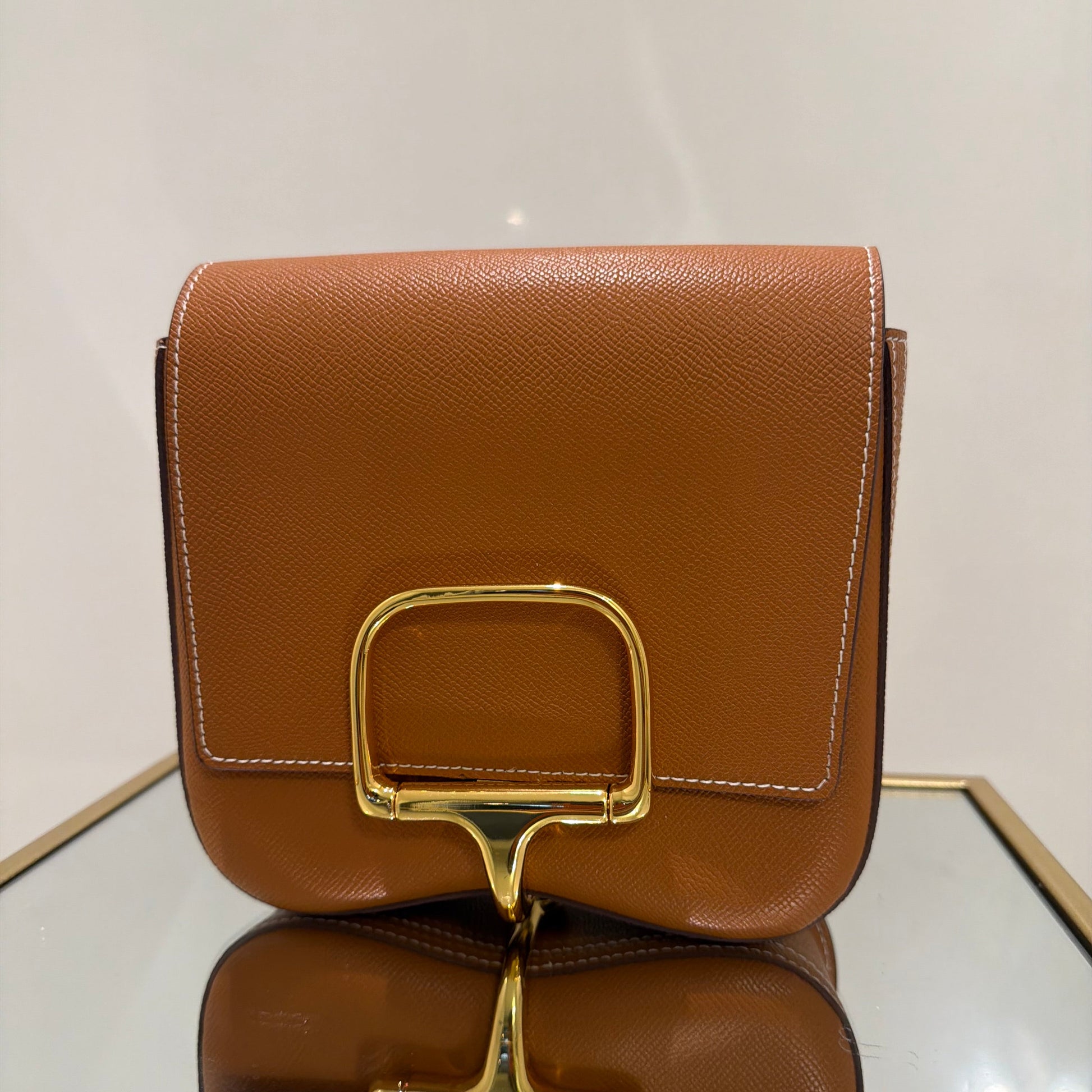 Brown handbag with gold hardware on a light background