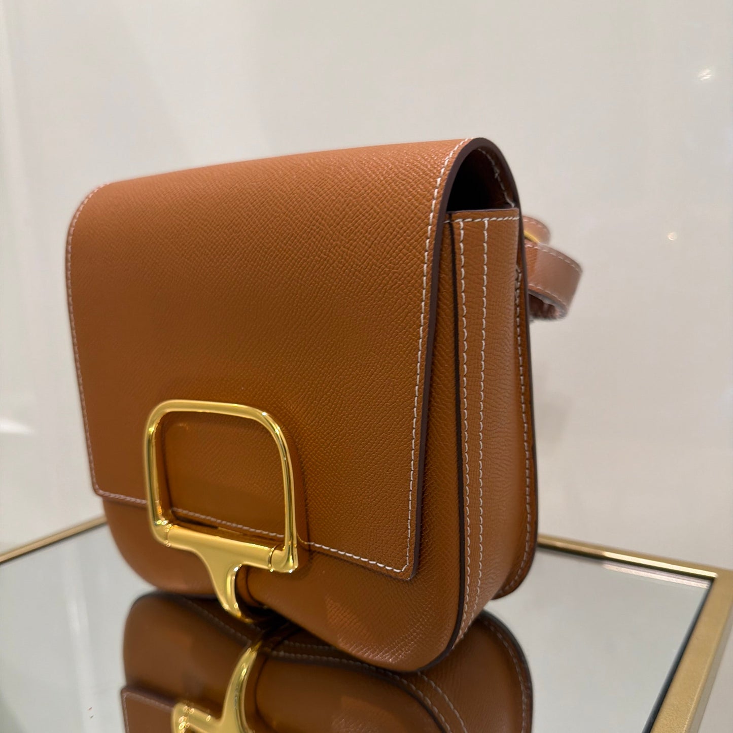 Brown leather bag with gold buckle on a white surface