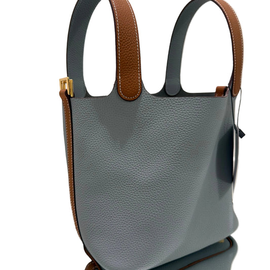 Gray handbag with brown handles on a light surface