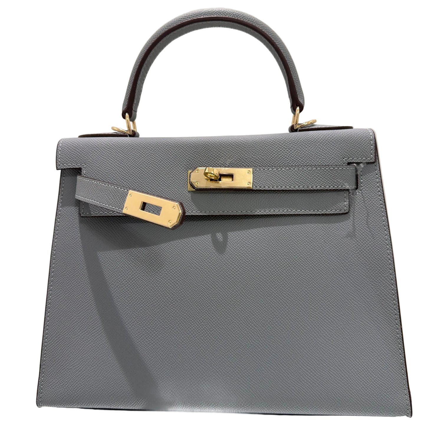 Gray handbag with gold accents on a light beige background