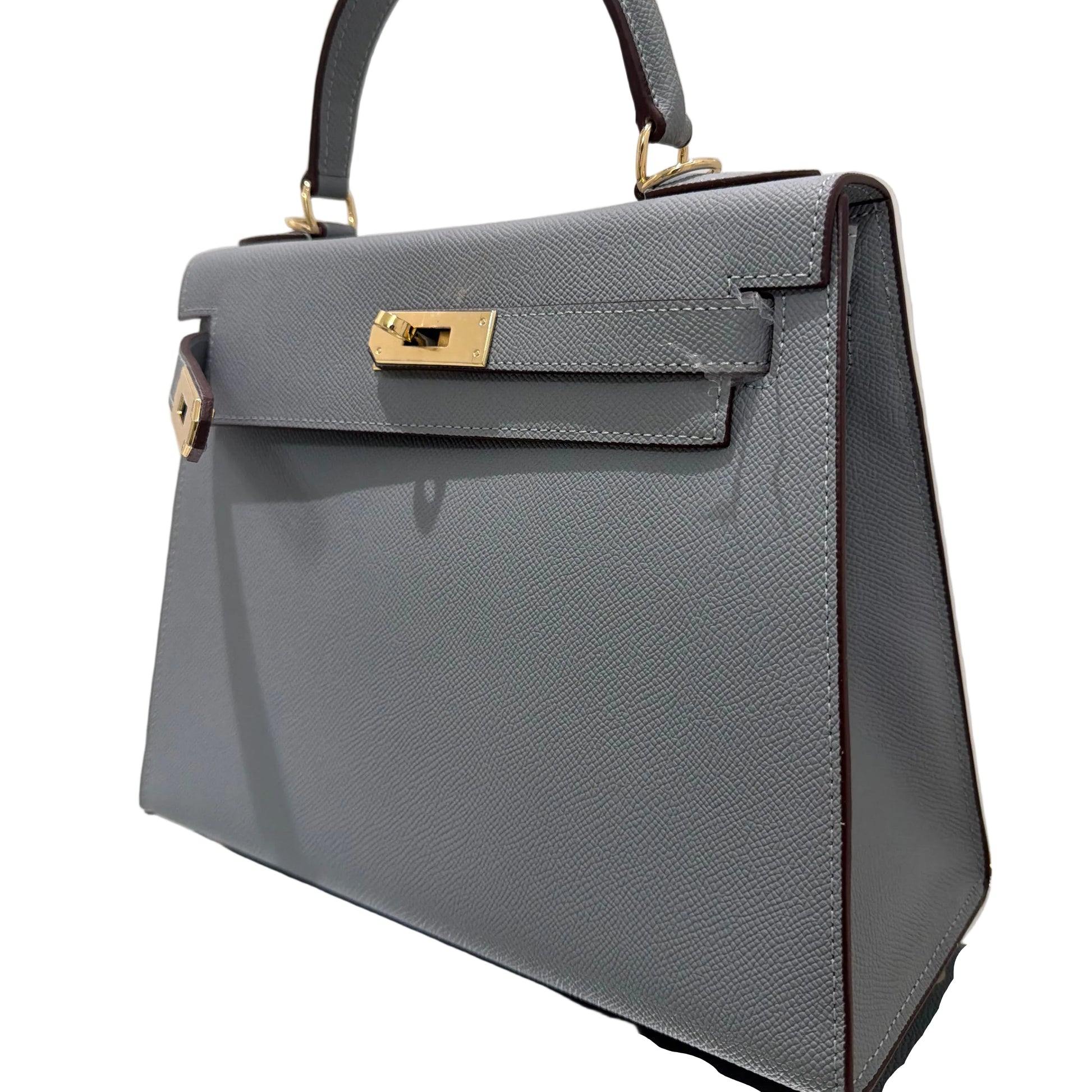 Gray handbag with gold accents on a reflective surface
