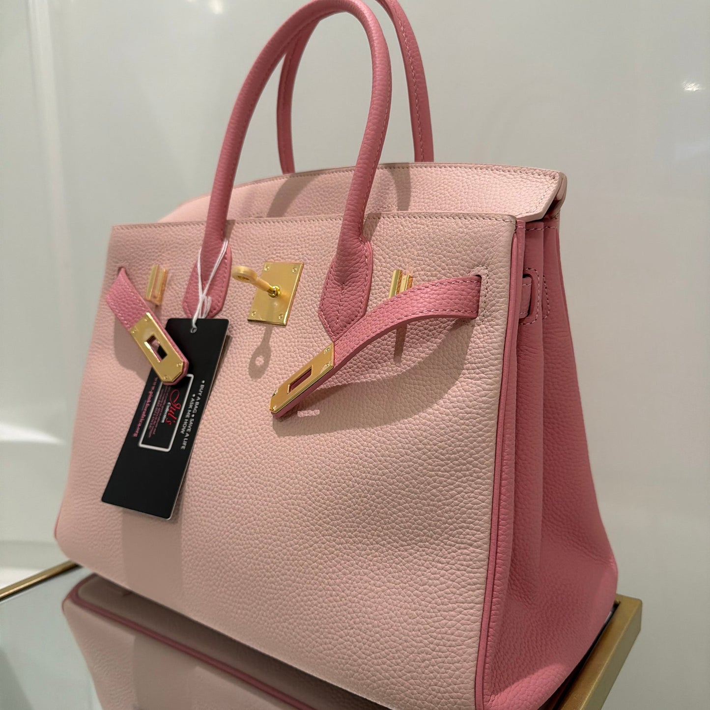 Pink handbag with gold accents on a white surface