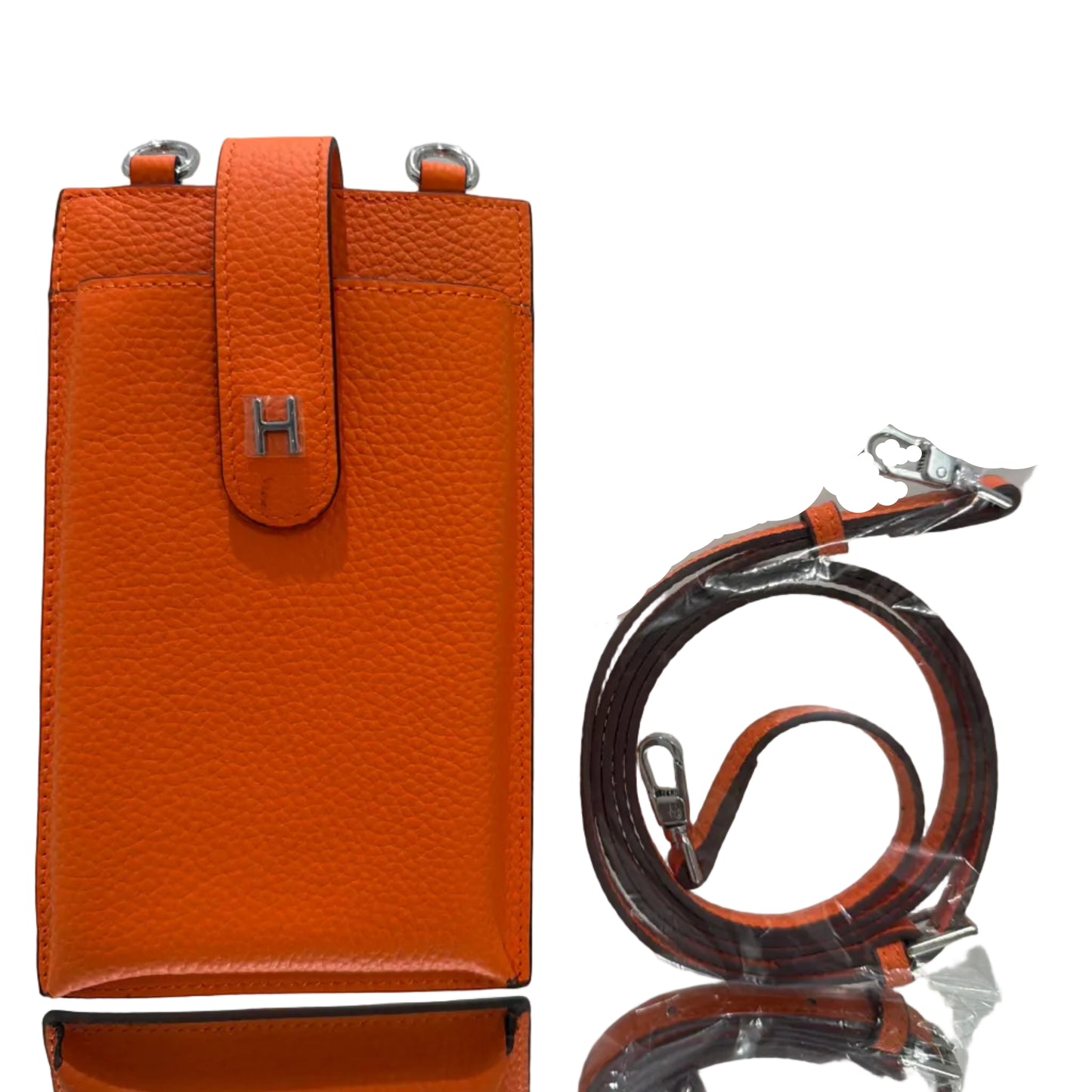 Orange leather handbag with a strap on a light gray background