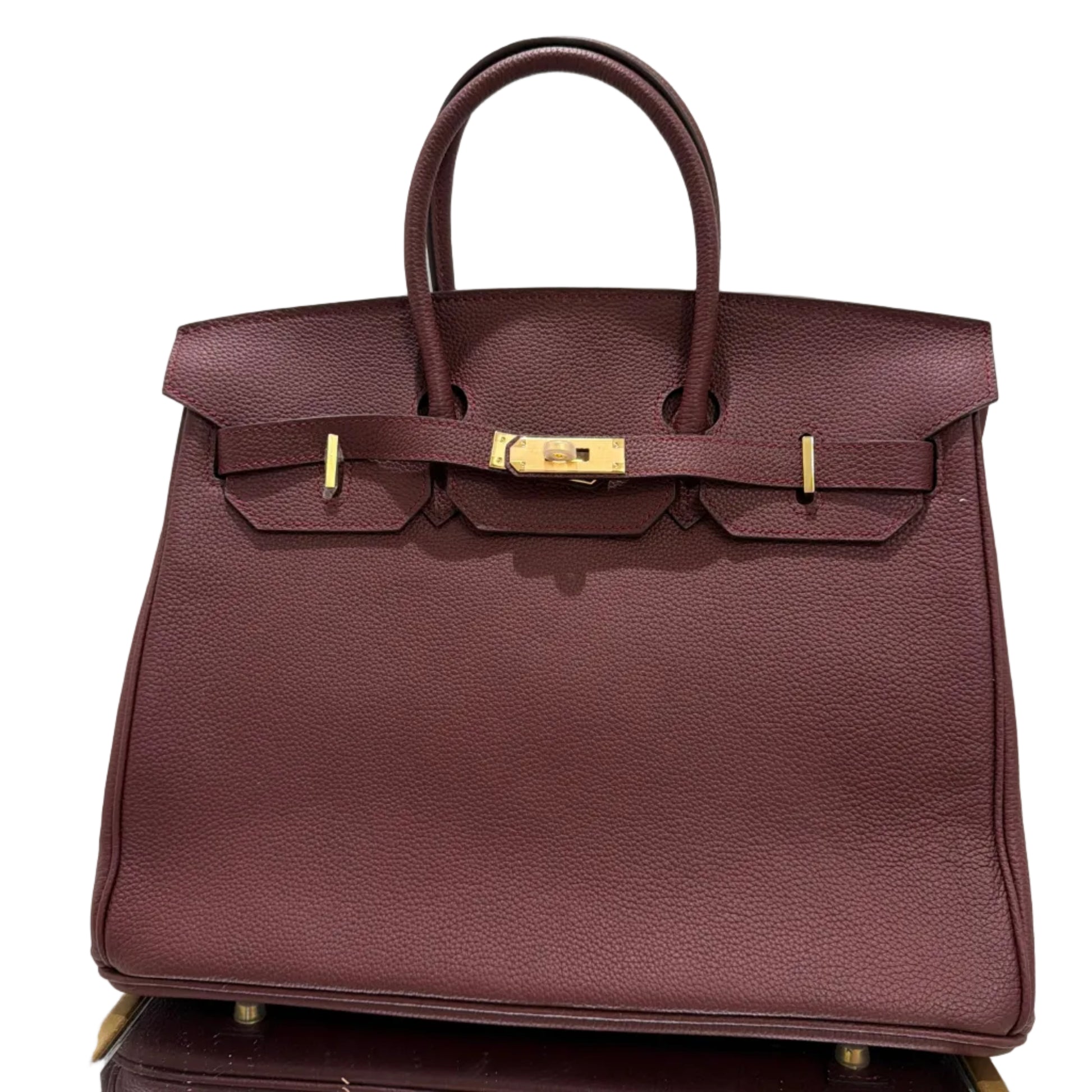 Brown leather handbag with gold hardware on a white background