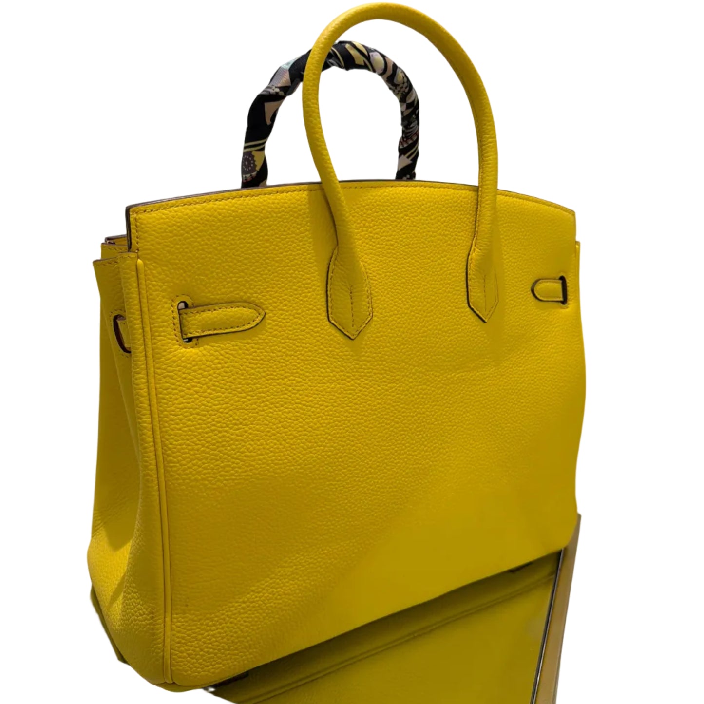 Yellow handbag on a white surface with a gold stand