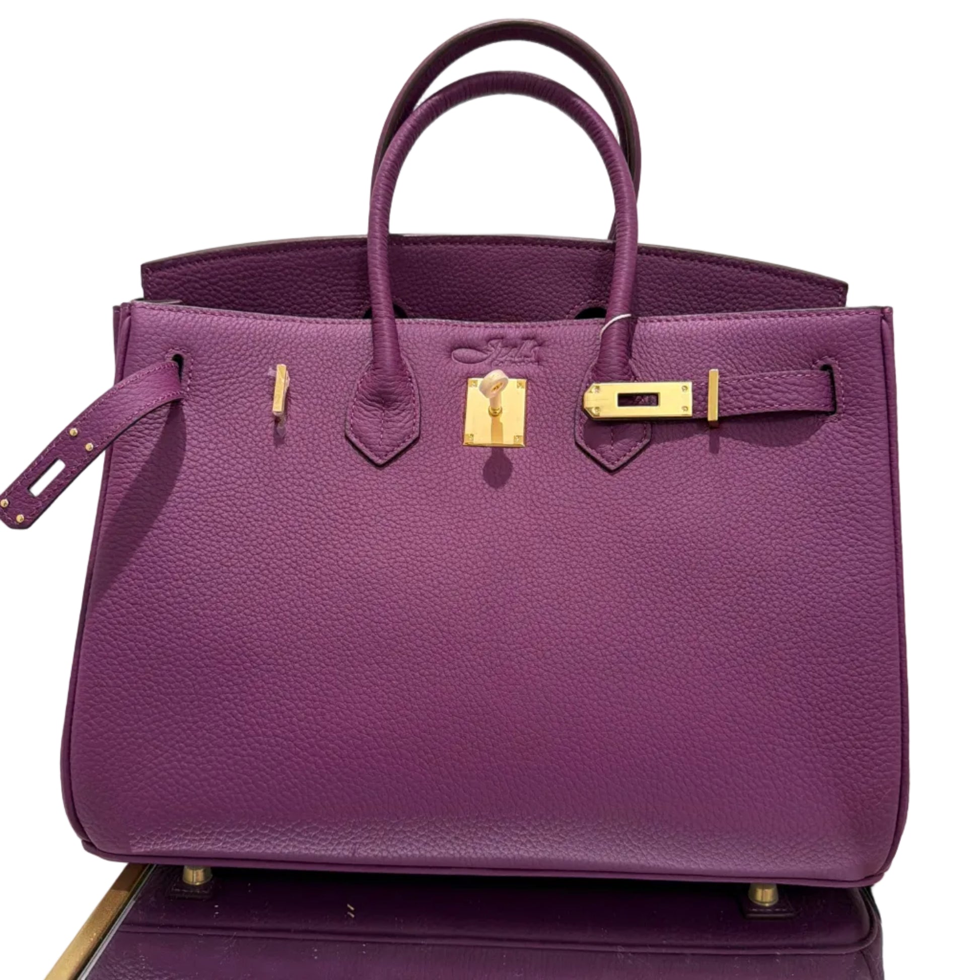 Purple handbag with gold hardware on a white background