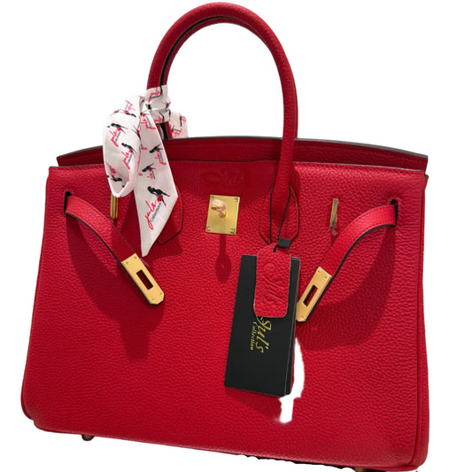 Red handbag with gold accents and a visible brand tag on a white background