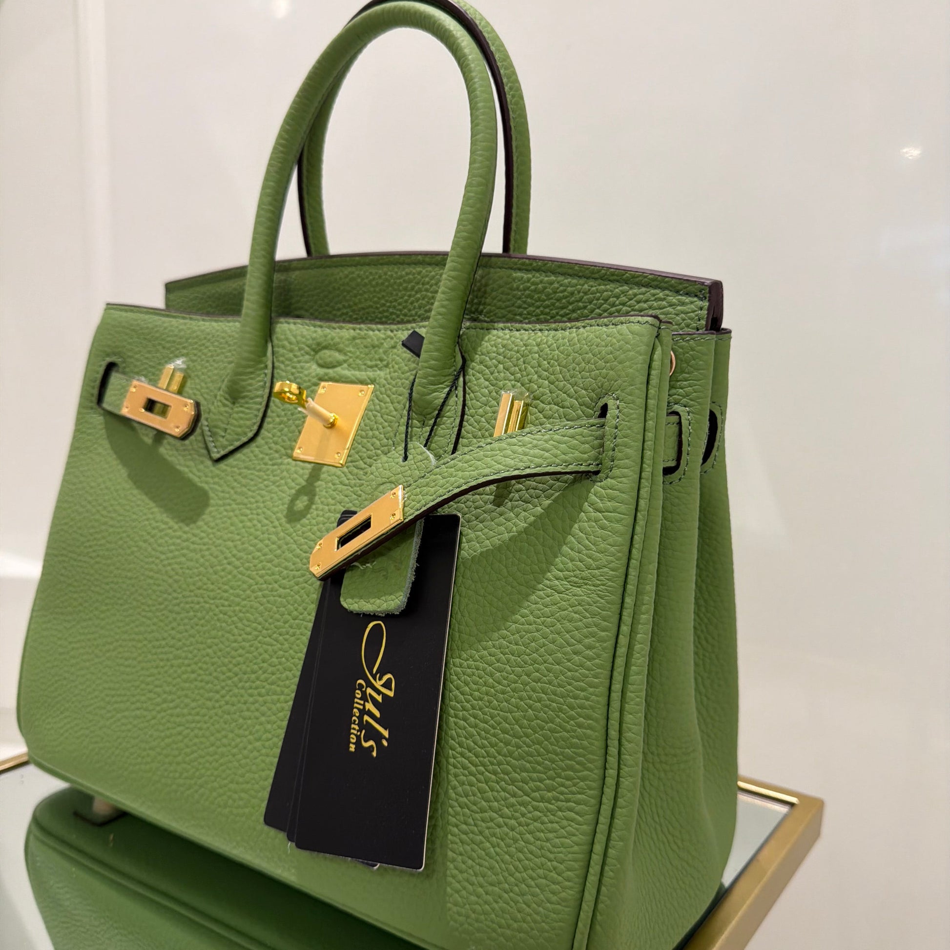 Green handbag with gold hardware on a white background