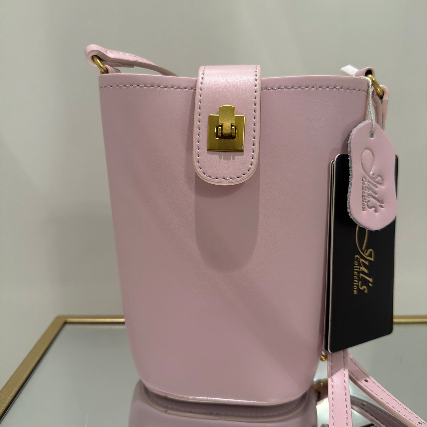 Pink handbag with gold clasp on a light gray background