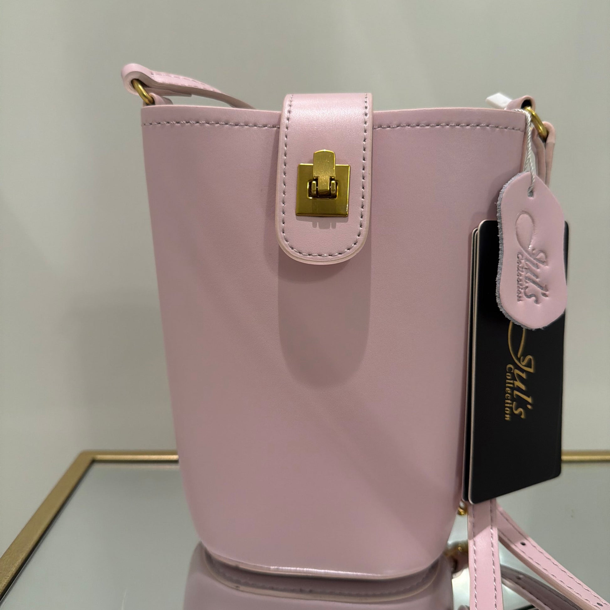 Pink handbag with gold clasp on a light gray background