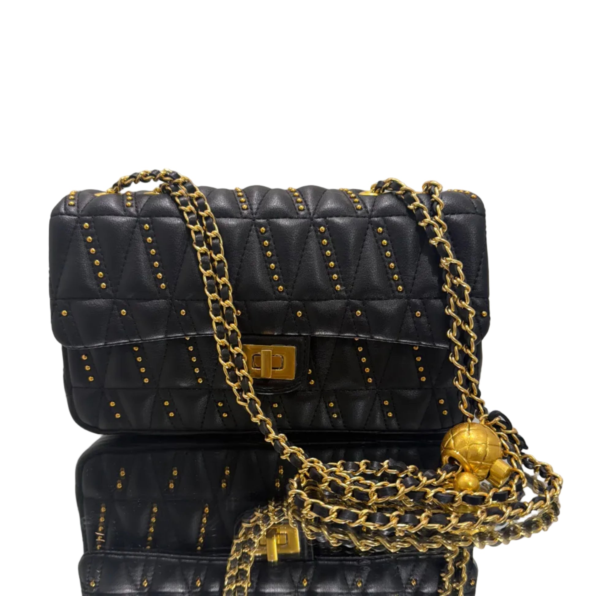 Black quilted handbag with gold chain strap on a light gray background
