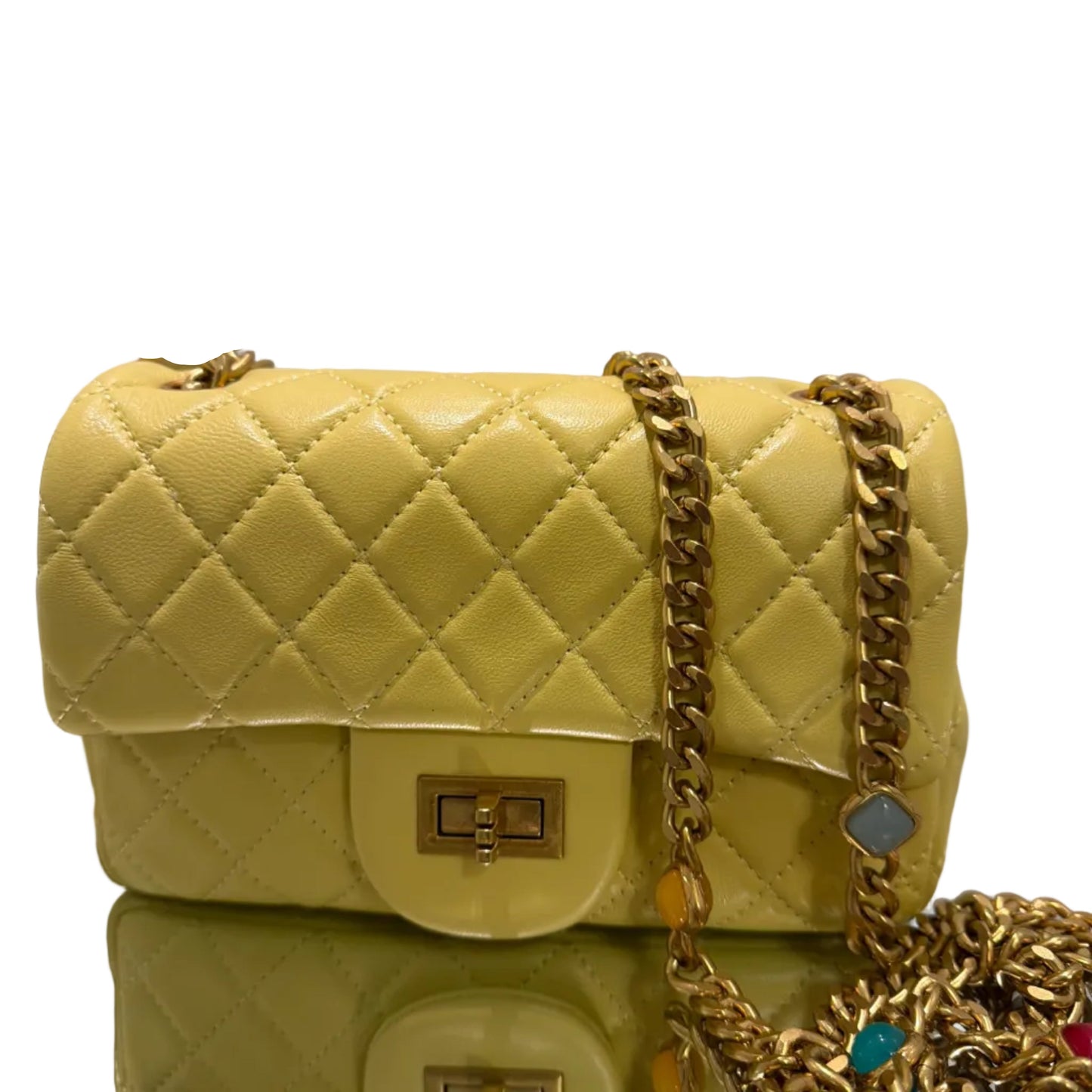 Quilted yellow handbag with gold chain and decorative elements on a gray background