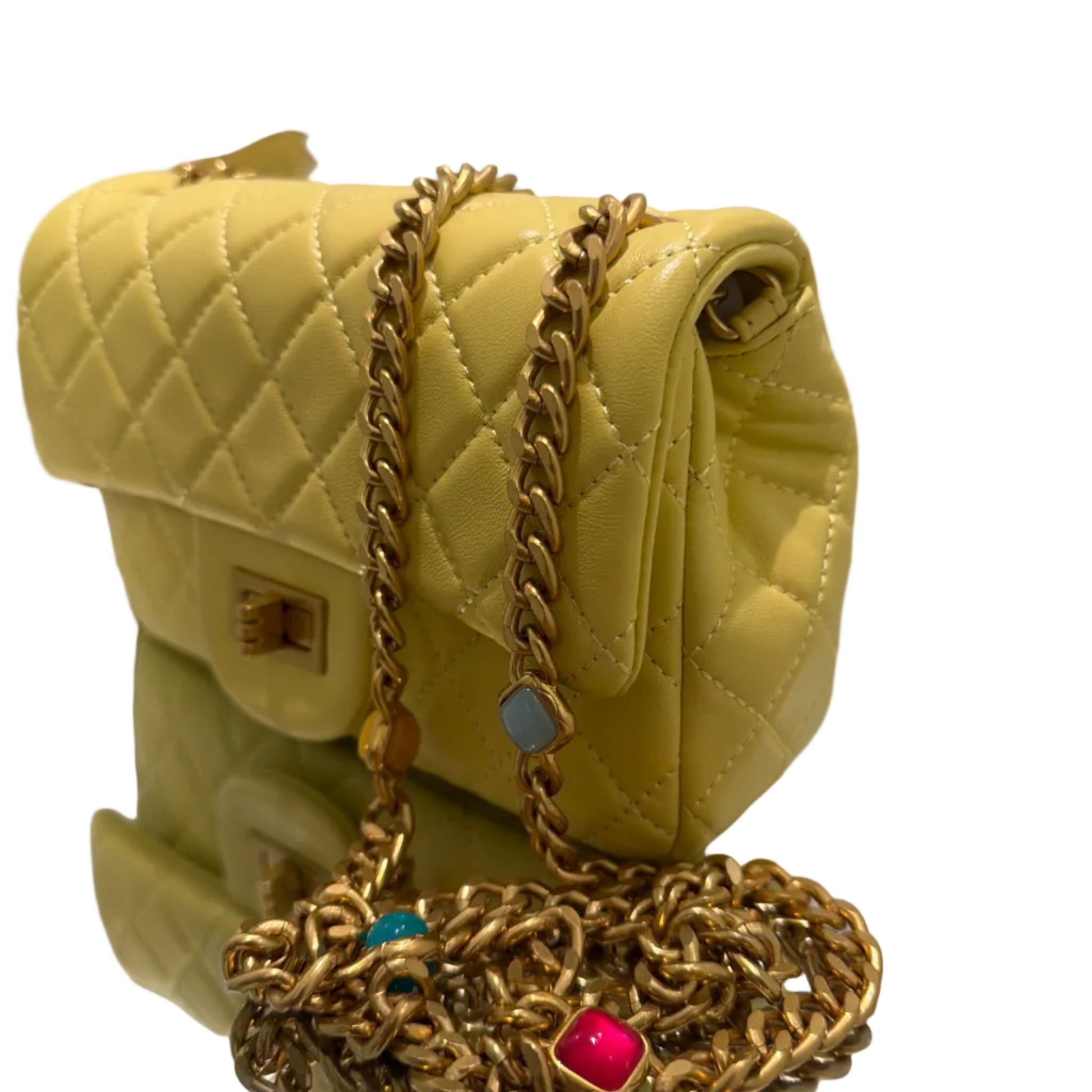 Yellow quilted handbag with gold chain and decorative clasp on a white background