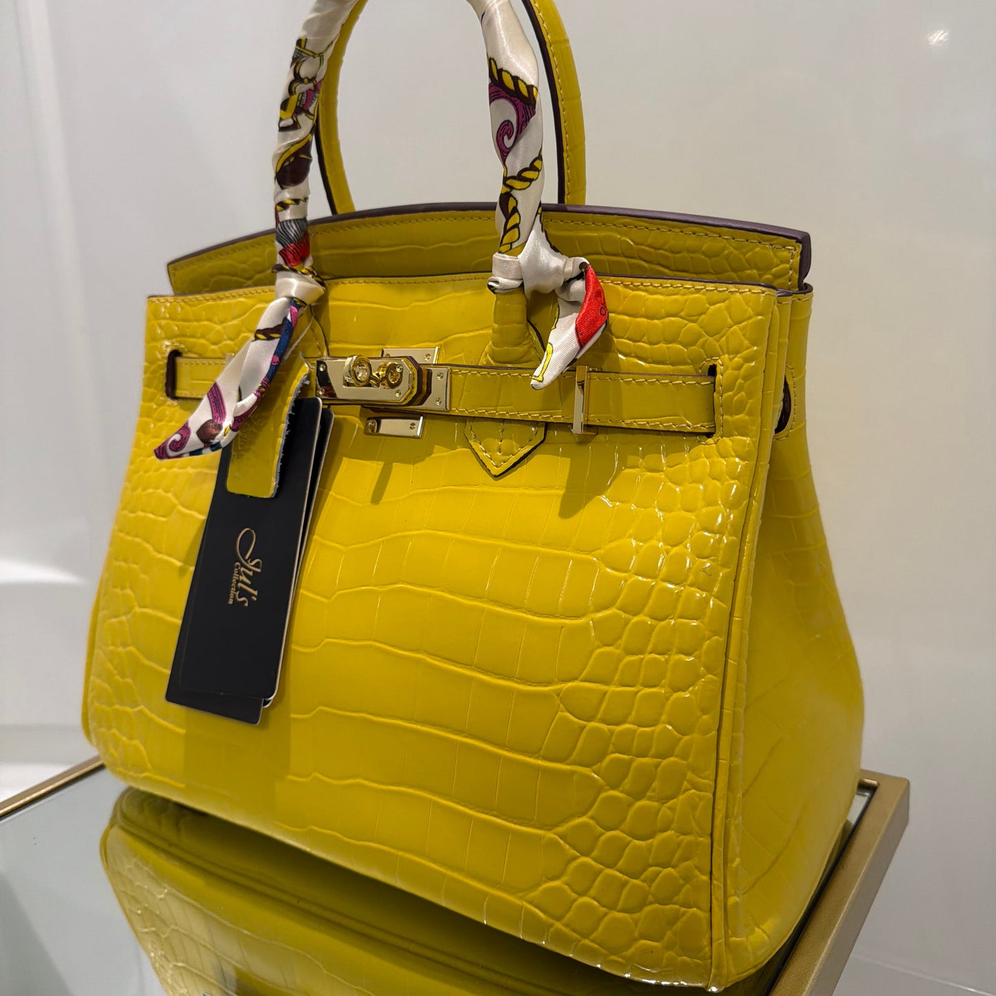 Yellow crocodile-patterned handbag with a colorful handle on a white background