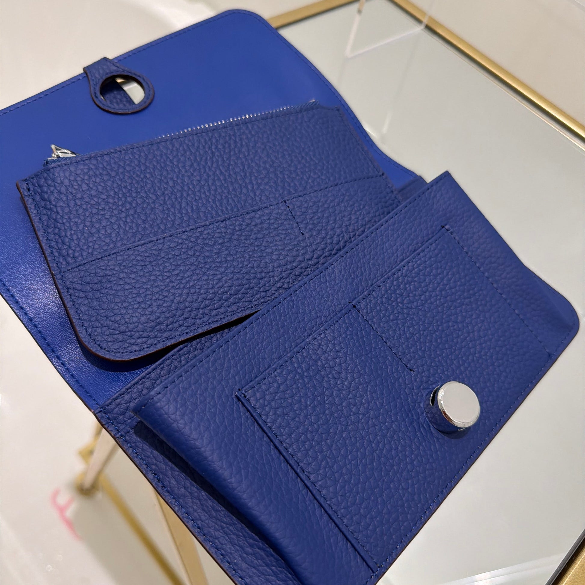 Blue leather wallet on a glass surface with a white tiled background