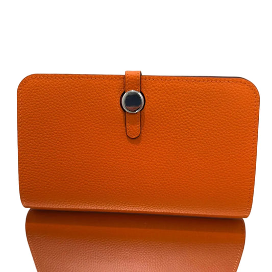 Orange leather wallet with a strap on a light gray background