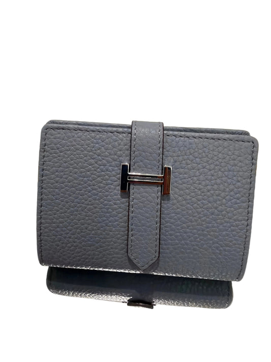 Gray textured wallet with a silver buckle on a light gray background