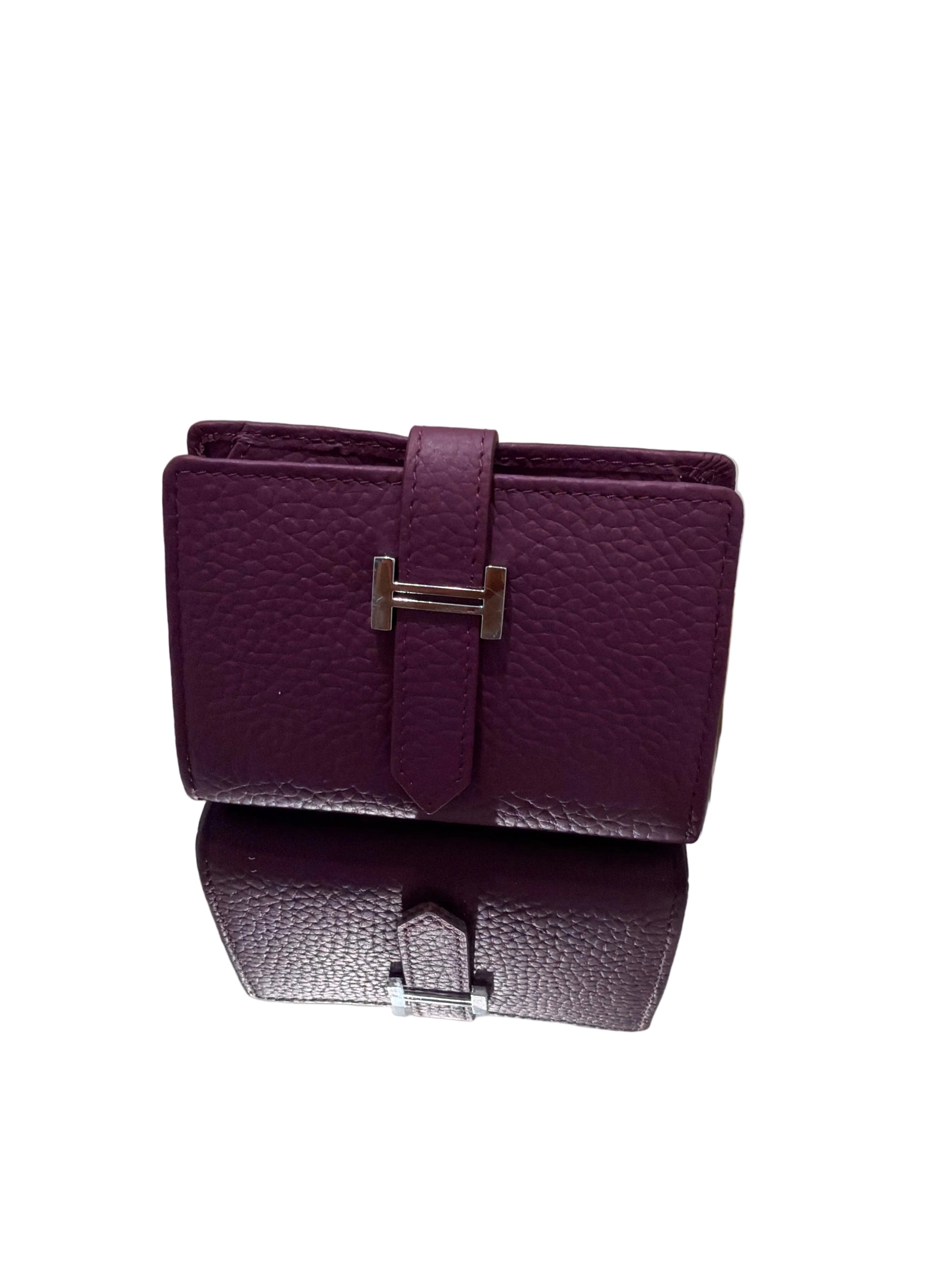 Purple textured handbag with silver buckle on a stand against a light background