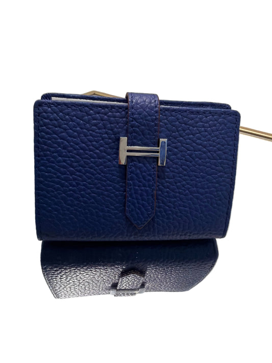Blue textured wallet with silver buckle on a clear stand