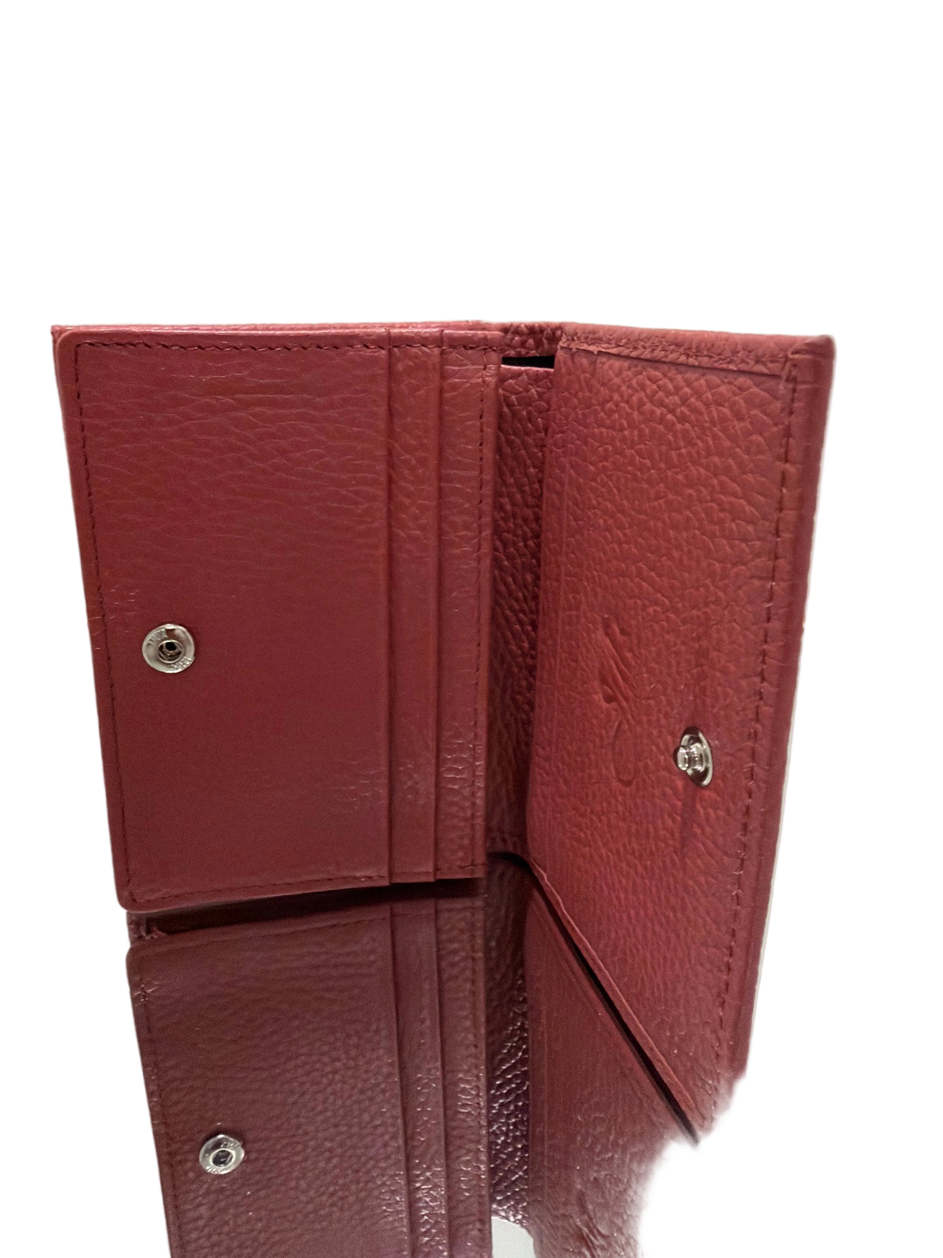 Red leather wallet with metallic buttons on a light gray background