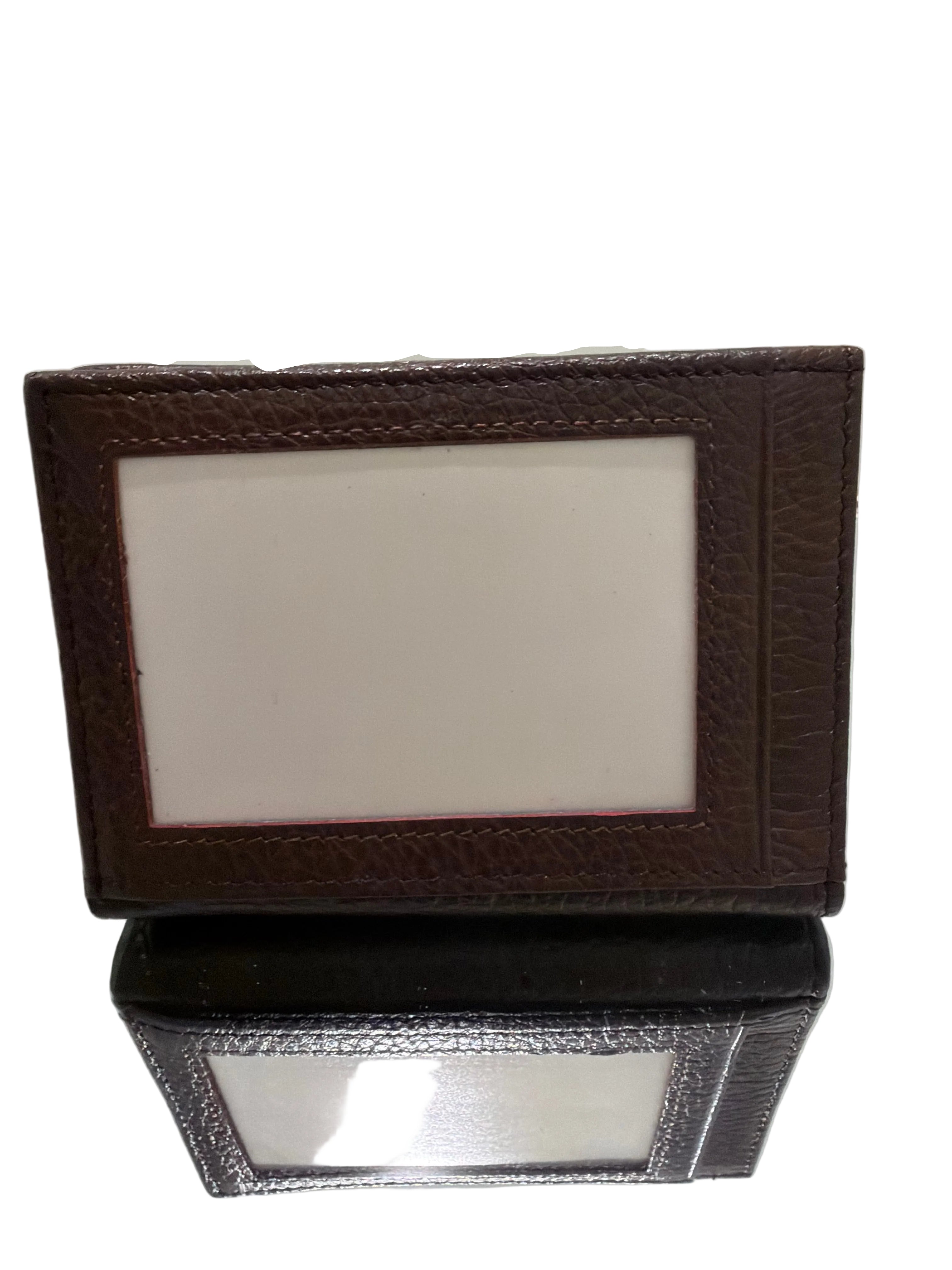Two leather-bound photo frames on a white surface