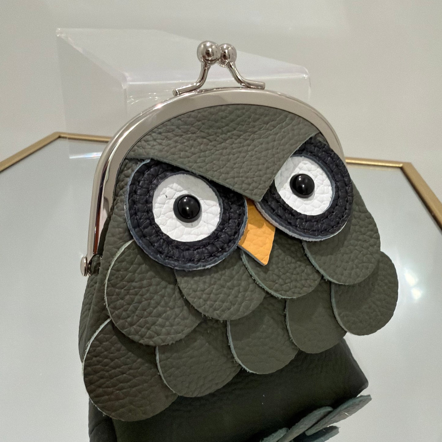 Gray owl-shaped pouch with a mirror on a white background