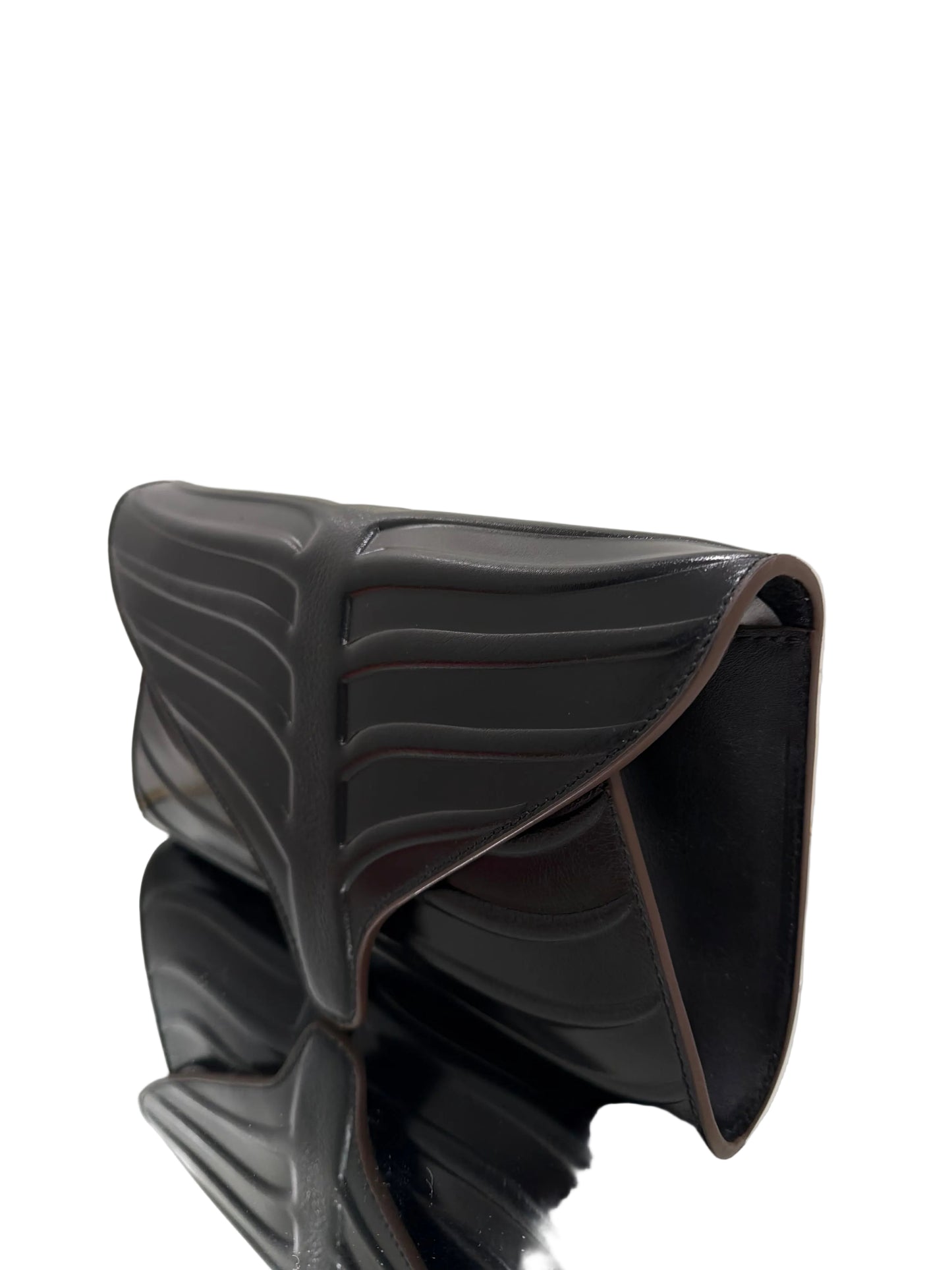 Black shoe trees on a white surface with a mirror reflection.