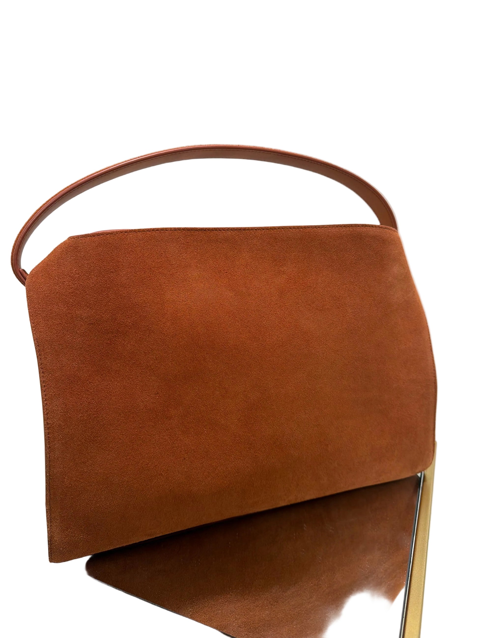 Brown leather bag on a white surface with a gold frame