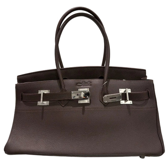 Dark brown leather handbag with silver hardware on a light beige background