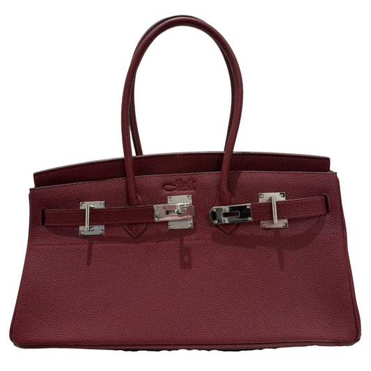 Burgundy handbag with silver hardware on a light gray background