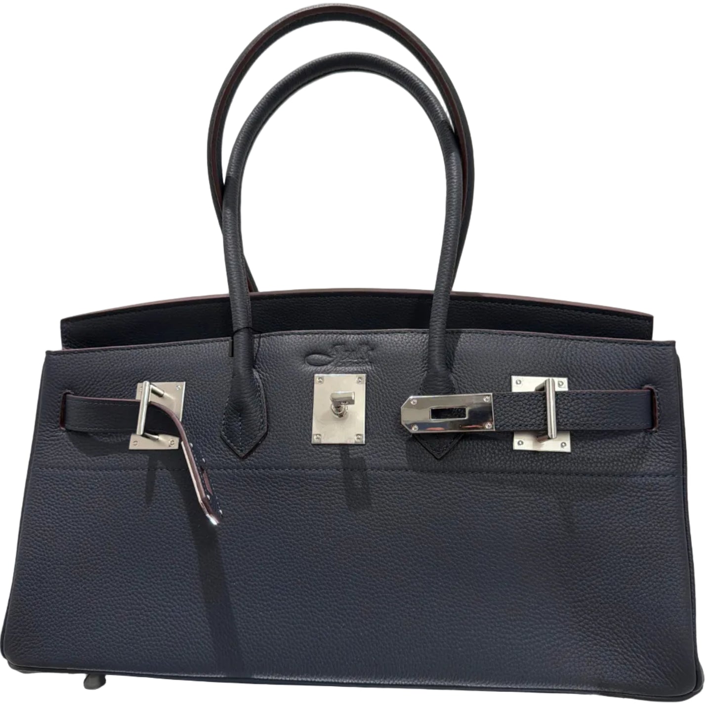 Black leather handbag with silver hardware on a light gray background