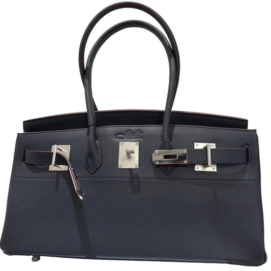 Black leather handbag with silver hardware on a light gray background