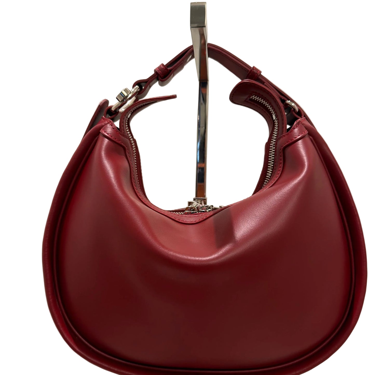 Maroon handbag with a gold handle on a light beige background
