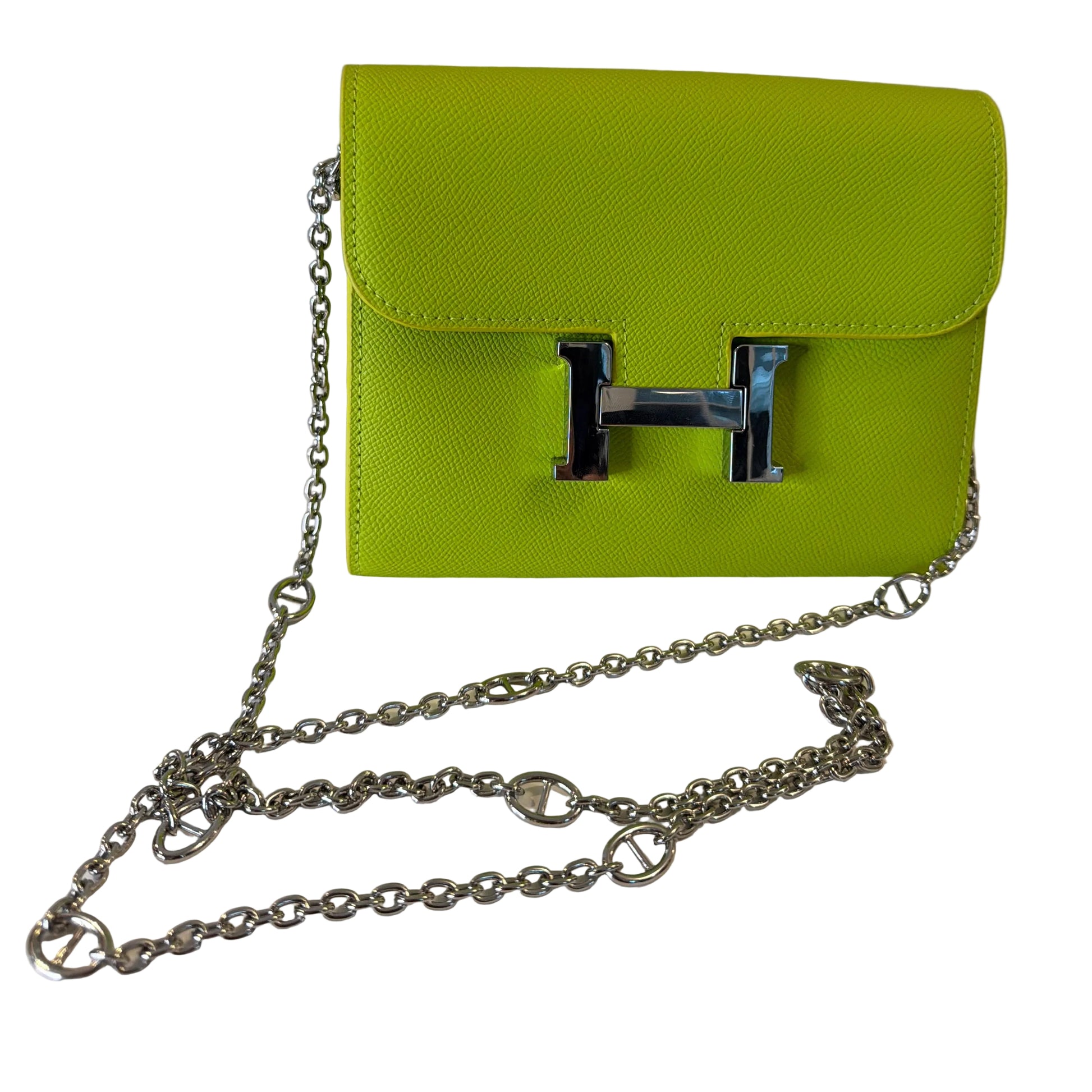 Green handbag with a silver chain on a white surface