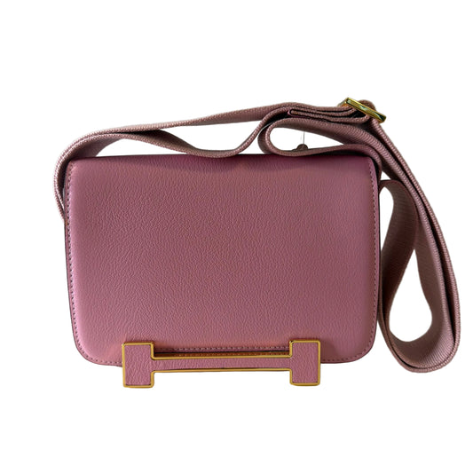Pink handbag with gold accents on a light gray background