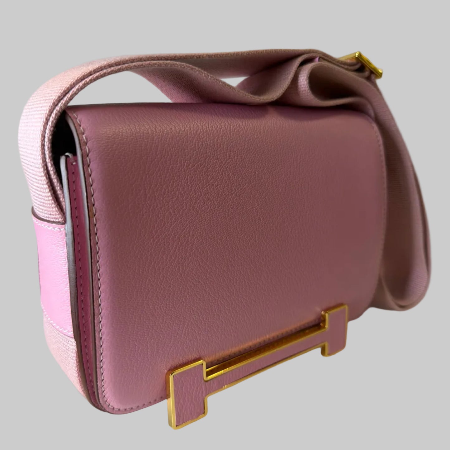 Pink handbag with gold accents on a light gray background