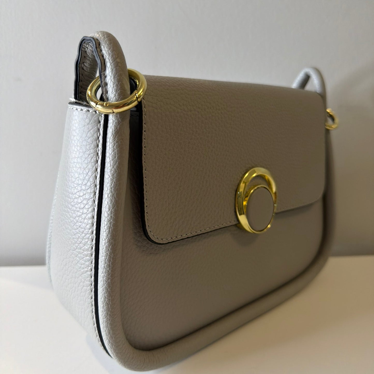 Close-up of a beige handbag with gold accents on a white background