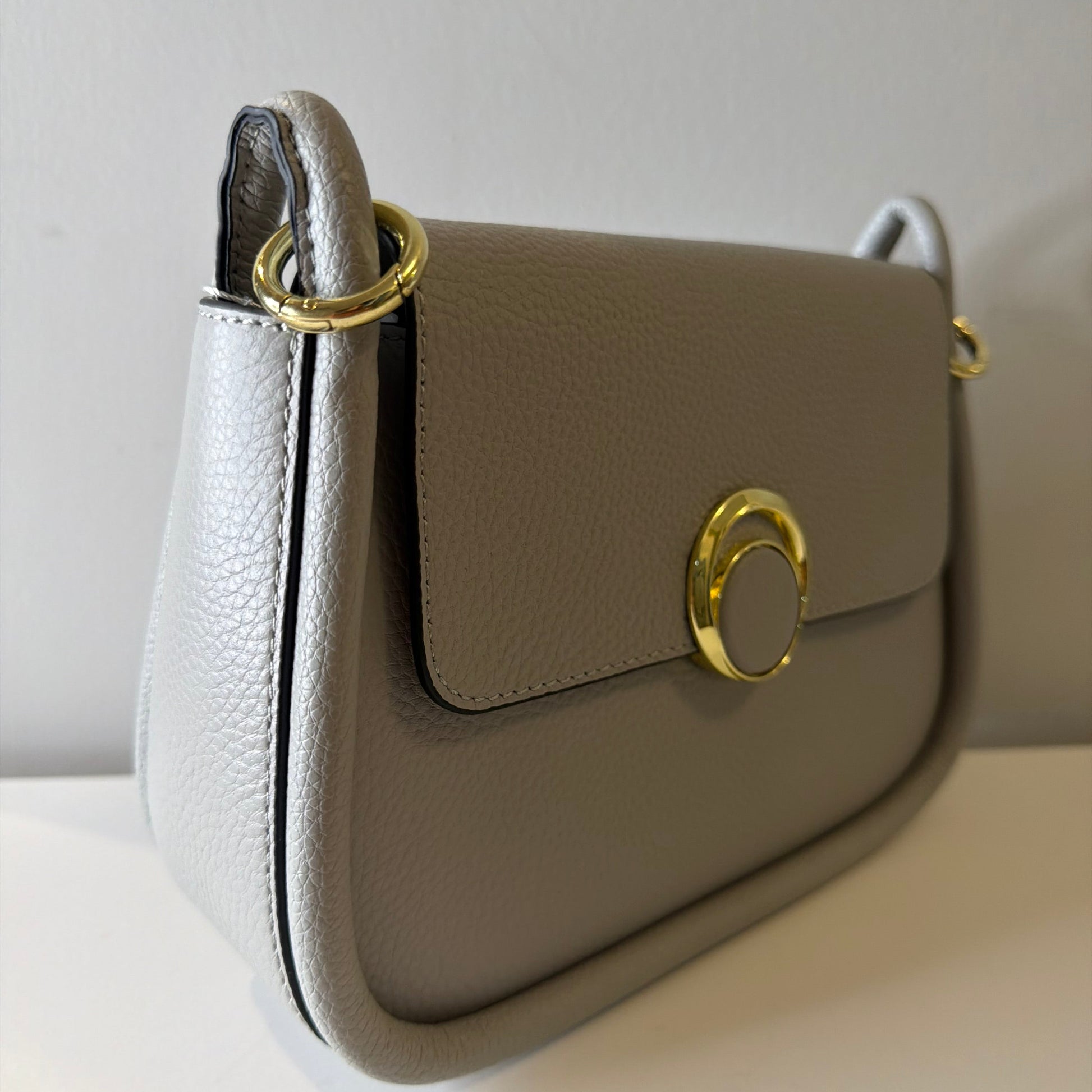 Close-up of a beige handbag with gold accents on a white background