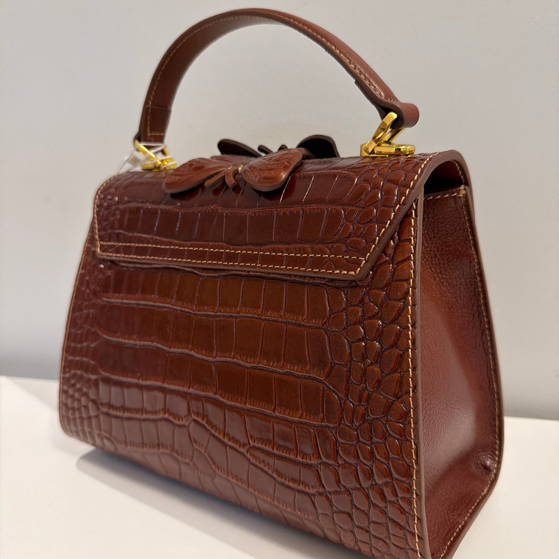 Brown textured handbag with a handle on a light gray background