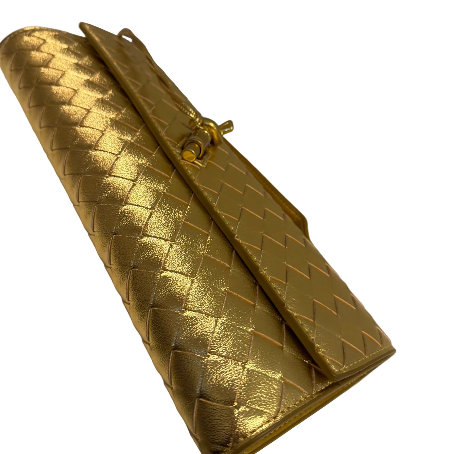 Gold woven handbag on a white surface with a gray background
